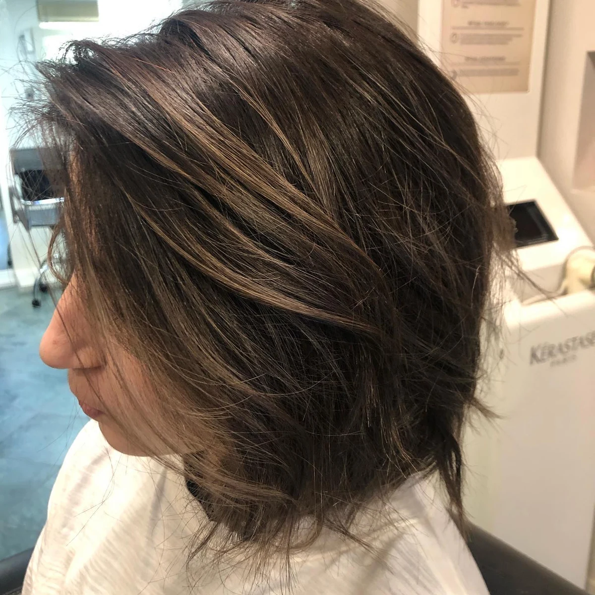 Detalle lateral de cabello oscuro trabajado en el salón.