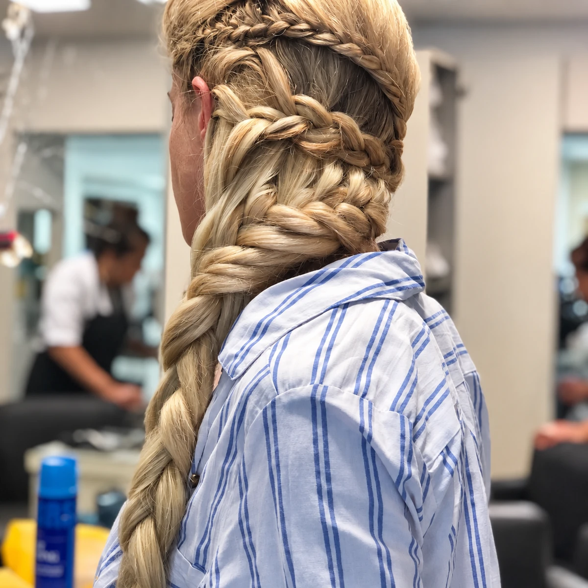 Trenza recogida con volumen y cola larga sobre una camisa a rayas.